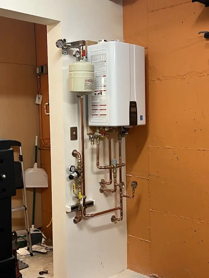 Plumbing technician inspecting water heater connections in Latimer